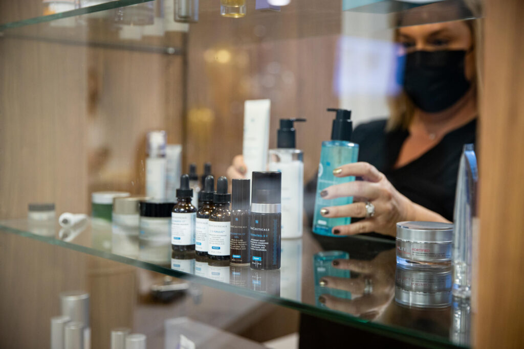 Staff member stocking skin care products on glass shelf