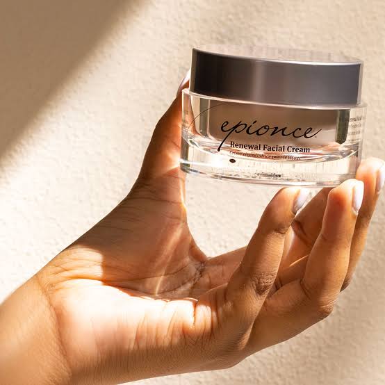 A hand holding a jar of Epionce Renewal Facial Cream in the sunlight