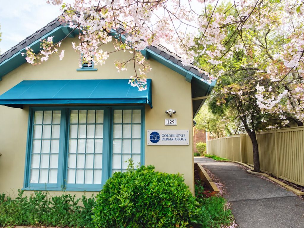 Golden State Dermatology's Los Altos office, a cottage with a teal awning under cherry blossoms