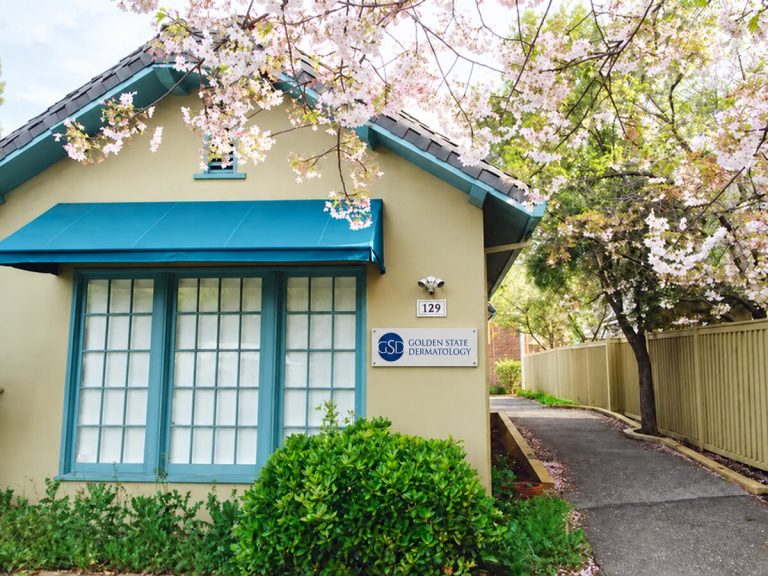 Golden State Dermatology's Los Altos office, a cottage with a teal awning under cherry blossoms