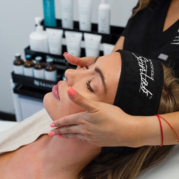 Esthetician gently massaging a relaxed client's face during a professional facial treatment