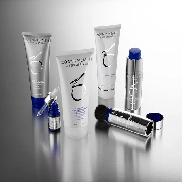 ZO Skin Health products: sunscreen, cleansers, hydrating creme, a serum and a powder brush on a silver surface